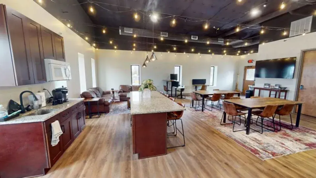 The main room at CoMission Lab — kitchen, lounge seating and work tables under string lights
